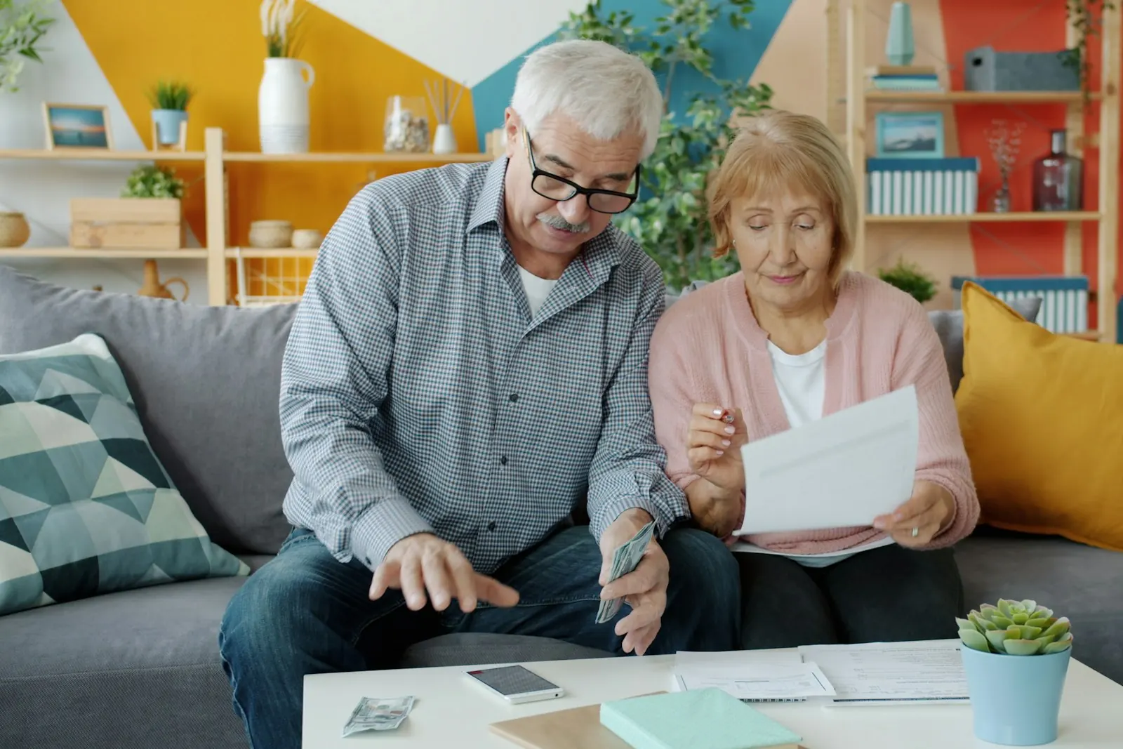 An older couple sitting on a couch at home reviewing documents together