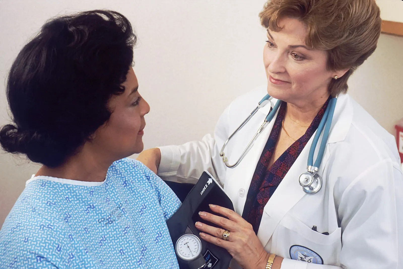 A clinician in a white coat talking with an adult patient during an office visit