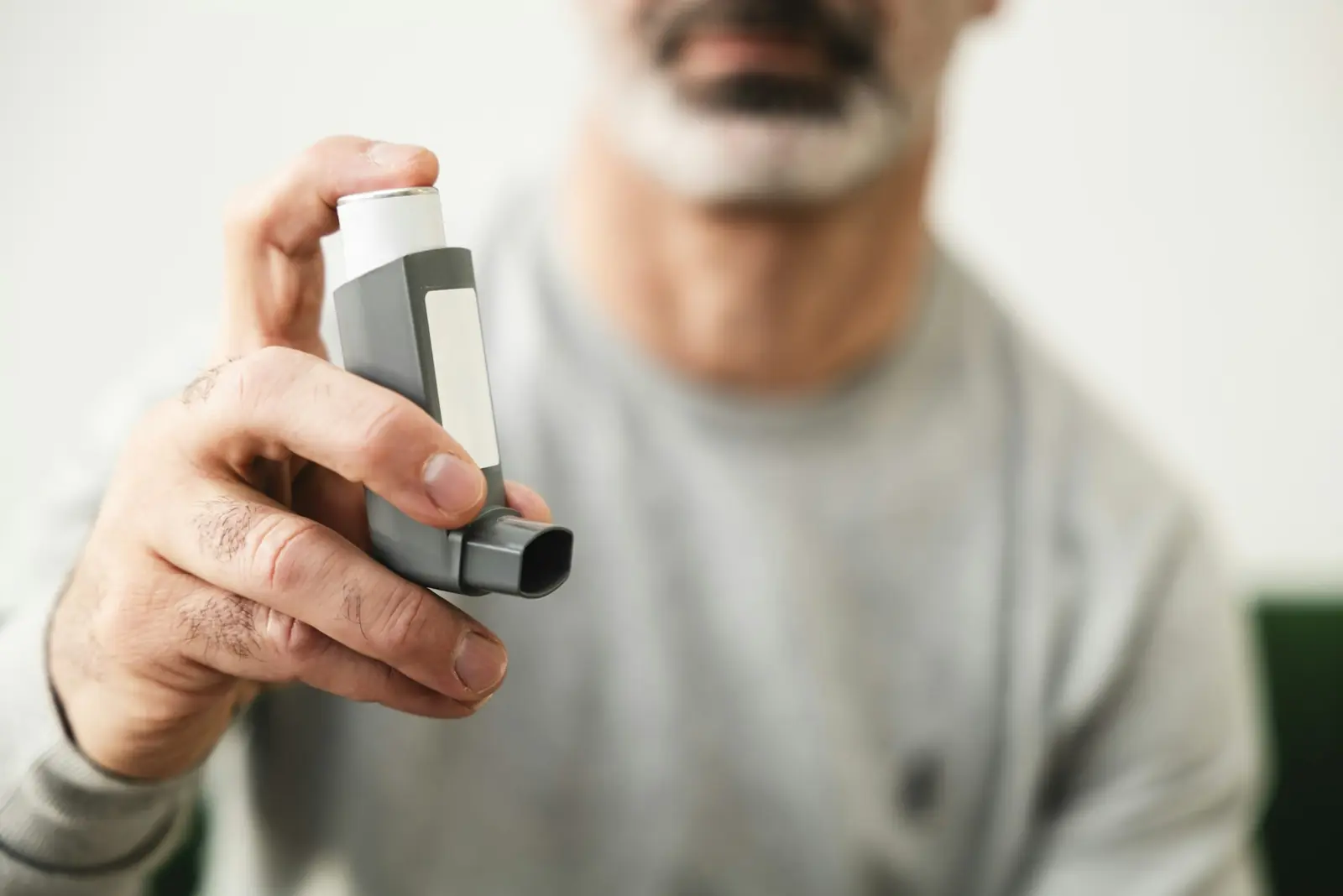 Older man holding an inhaler at home