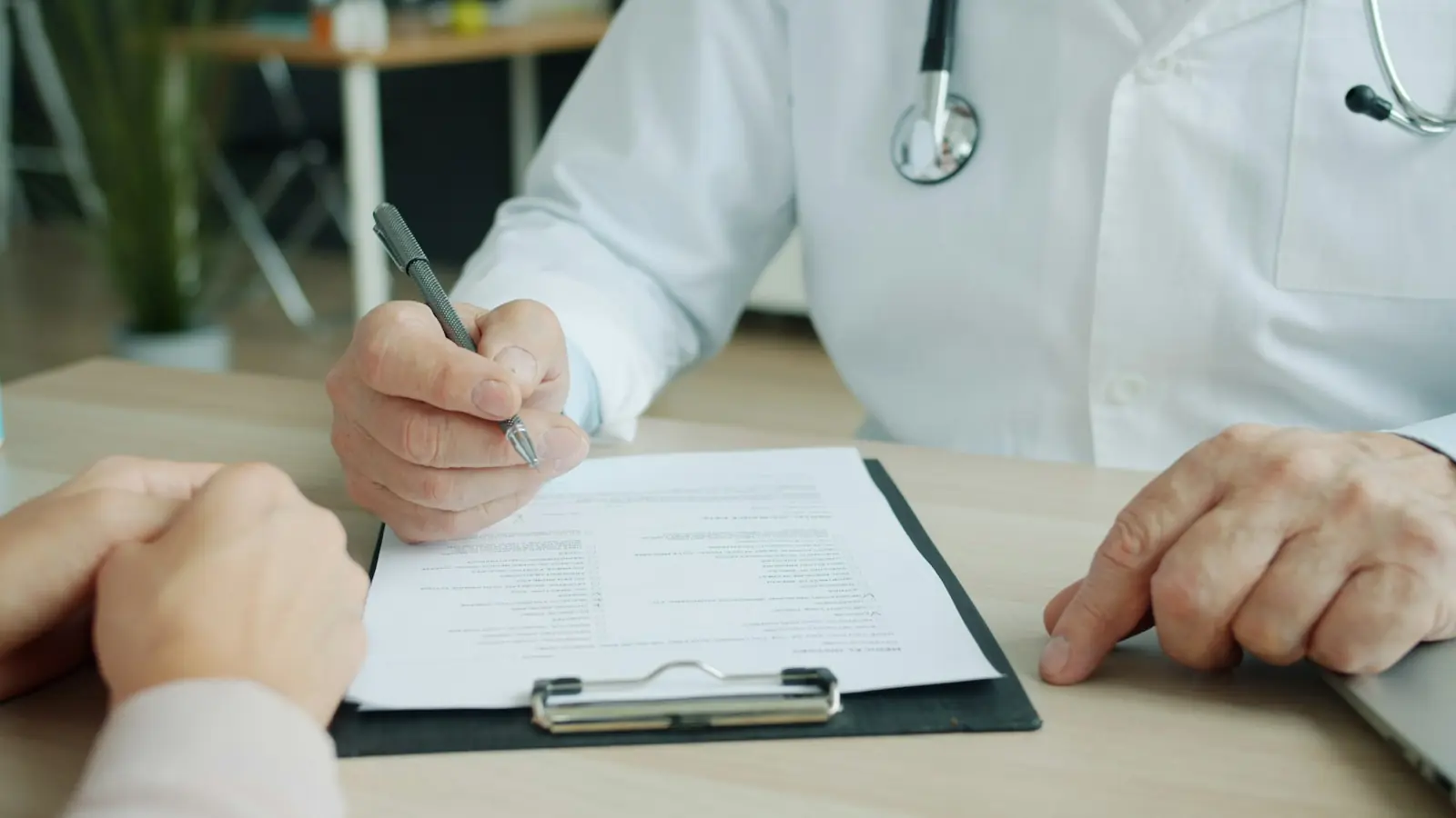 A person holding an insurance card while reviewing paperwork at a table