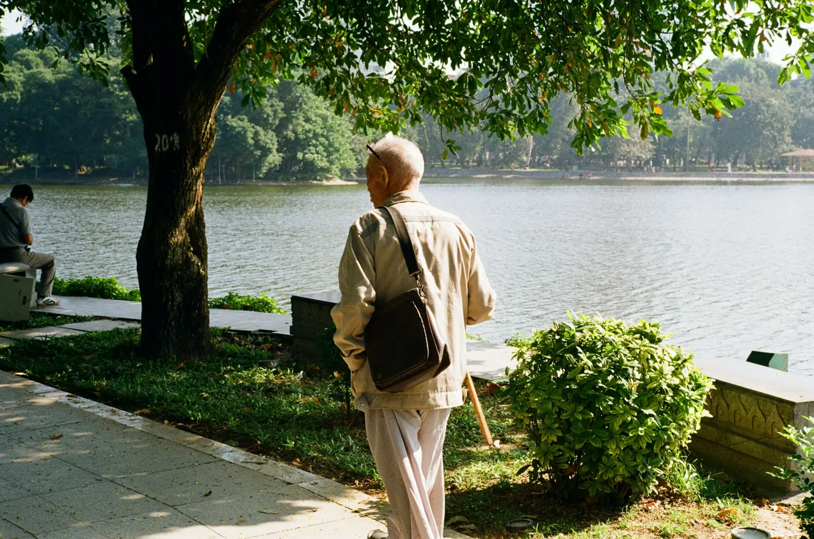 Older adult walking outdoors along a path beside a lake