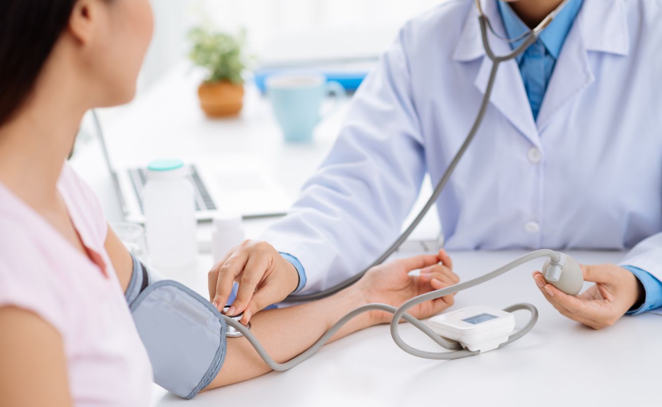 A healthcare professional checks a person's blood pressure using a cuff and monitor in a medical setting.